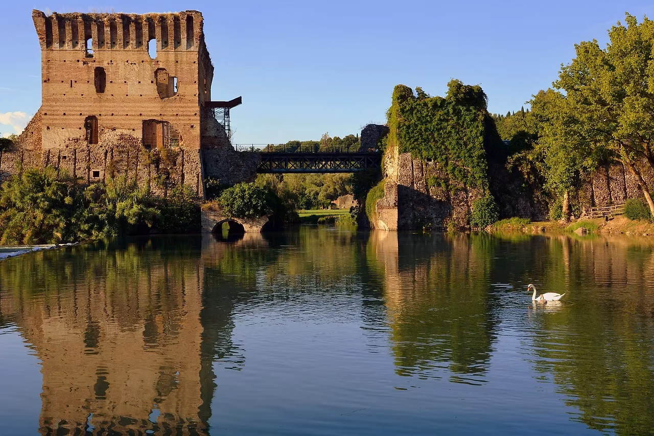De Ponte Visconteo en de oude molens van Borghetto sul Mincio, weerspiegeld in het water met een zwaan