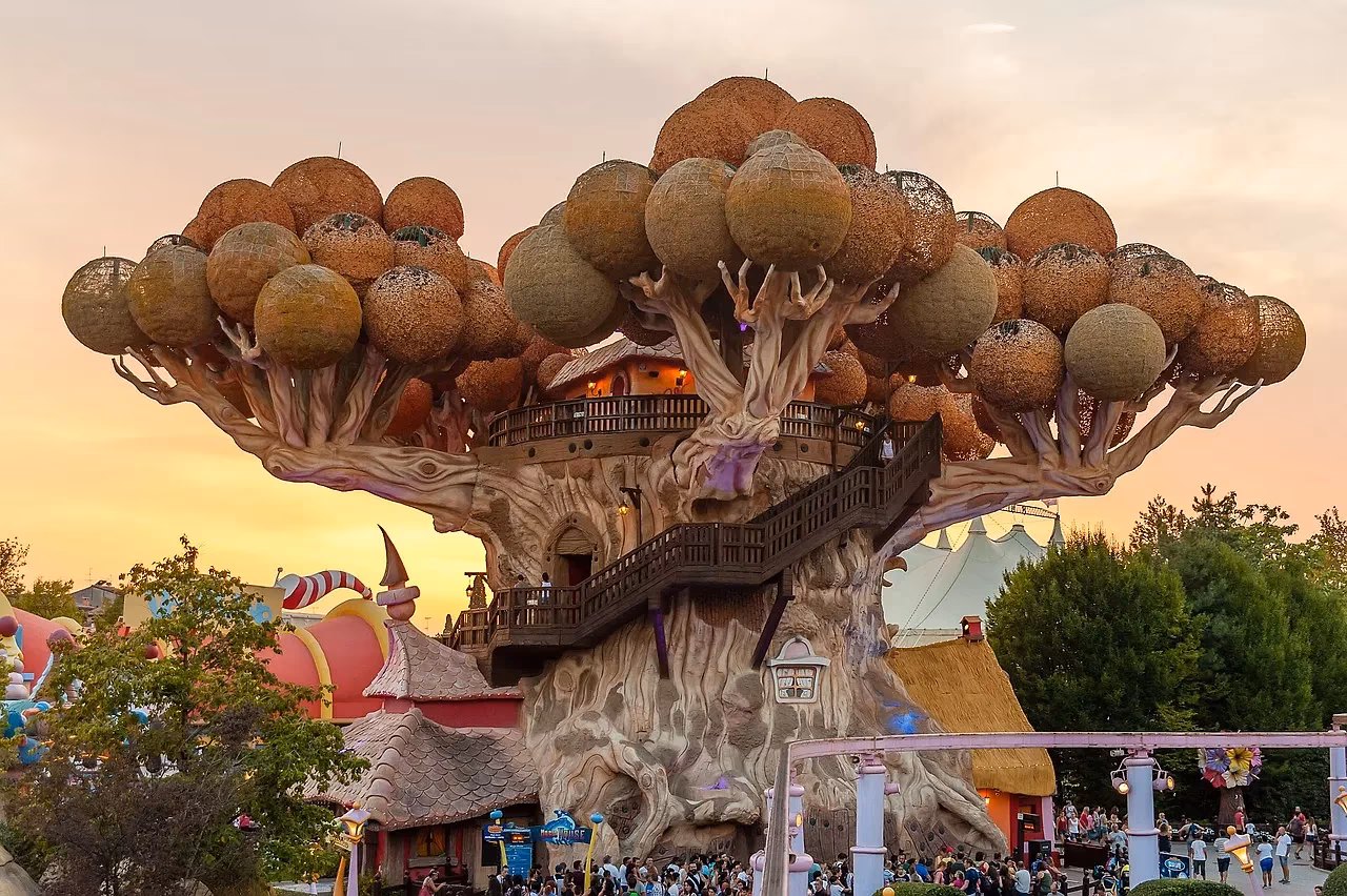 De grote boom met bolvormige hutten en trappen in Gardaland bij zonsondergang