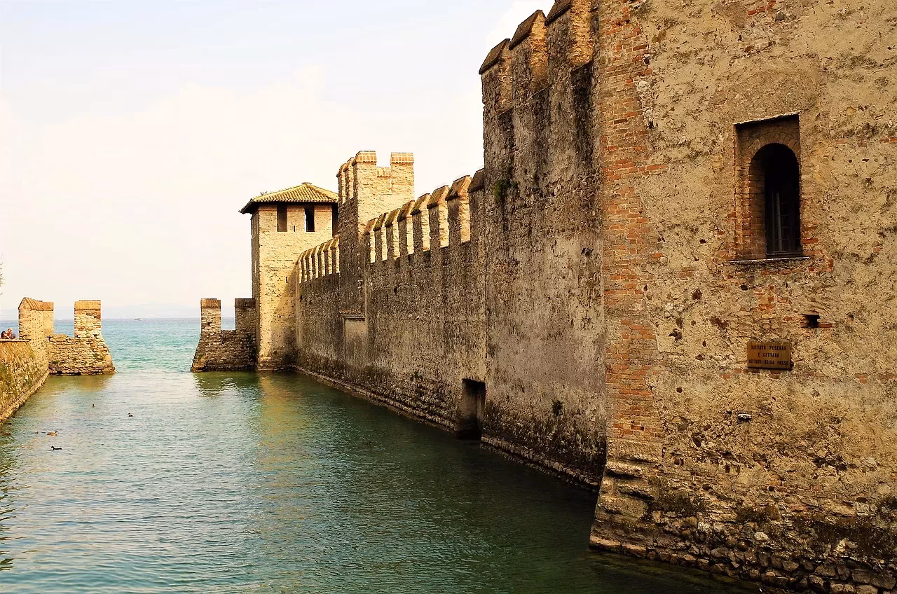 De gekrenelde muren en torens van het Castello Scaligero in Sirmione, die direct uit het water oprijzen